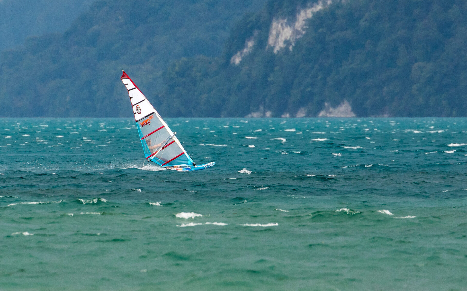 Windsurfer auf dem See vor den Bergen